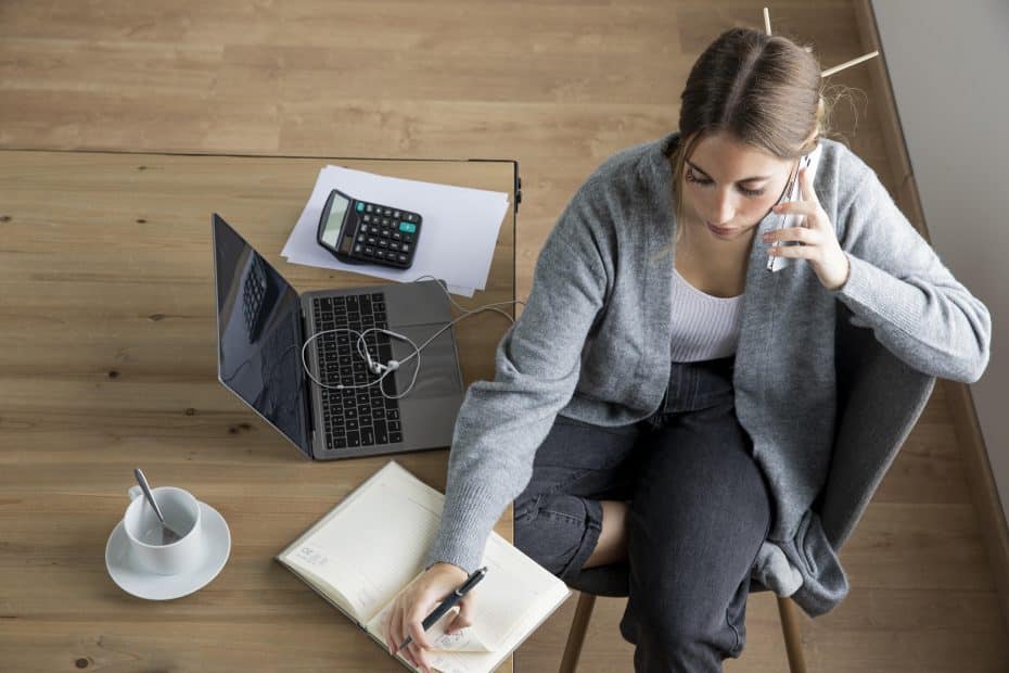 Mulher trabalhando ao telefone com o notebook aberto